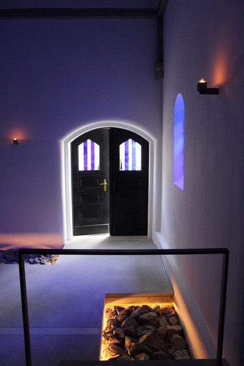 Ein blau beleuchteter Raum mit Blick zu einer schwarzen Tür