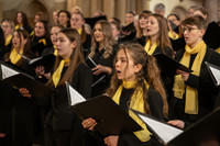 Mädchenchor in Schwarz mit gelbem Schal und Liedheften