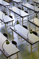 In Reihen angeordnete Tische mit jeweils zwei Stühlen und am Tisch montierten Leselampen aus Metall