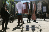 Kleiderständer auf Rollen mit Shirts und Kleidern auf Bügeln in der Fußgängerzone