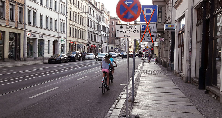 Straße mit Radfahrern und Verkehrsschildern Halteverbot und Parken durchgestrichen.