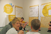 Kinder und Jugendliche sitzen im Naturkundemuseum in einem Raum zusammen und beraten sich.
