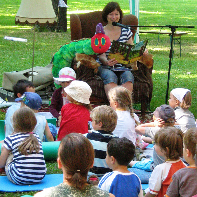 Kinder sitzen auf einer Wiese und hören einer Lesung beim Festival LeseLust im August zu