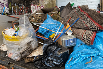unterschiedlicher Abfall mit Müllsäcken, alten Teppichen, Dosen und einem alten Radio auf einer Ladefläche.