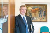 Prof. Dr. Dr. Thomas Vahlenkamp vor einem Bild mit einer Bauenhofszene mit einem Pferd