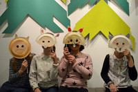 Vier Kinder halten sich selbst gebastelte Masken aus Pappe in Tierform vor das Gesicht.
