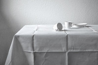 Tische mit einer weißen Tischdecke und zwei Tassen und einem Teller