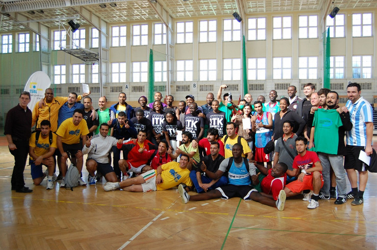 Mitglieder verschiedener Fußballmannschaften mit unterschiedlicher kultureller Herkunft stehen als Gruppe in einer Sporthalle 
