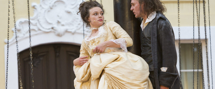 Eine Frau in barocker Kleidung blickt etwas ängstlich auf den hinter ihr stehenden Mann.