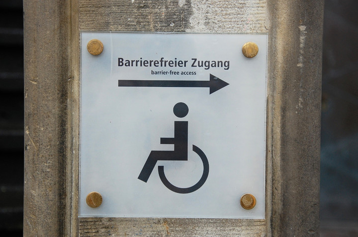 Ein Schild mit dem Piktogram eines Rollstuhlfahrers mit einem Pfeil und dem Schriftzug barrierefreier Zugang