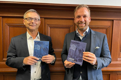 Zwei Männer stehen nebeneinander und halten die Broschüre in ukrainischer und in deutscher Sprache in den Händen