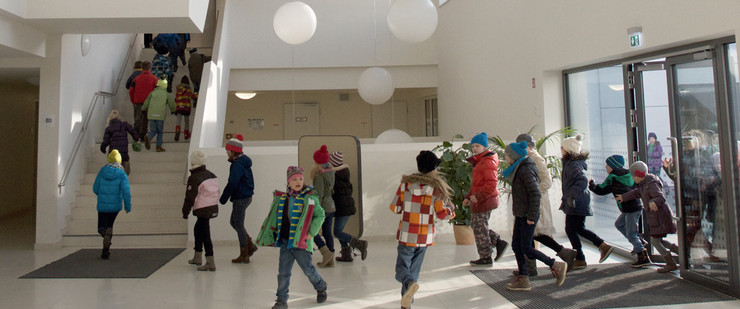 A group of kids is running through the entrance area of ​​a school.