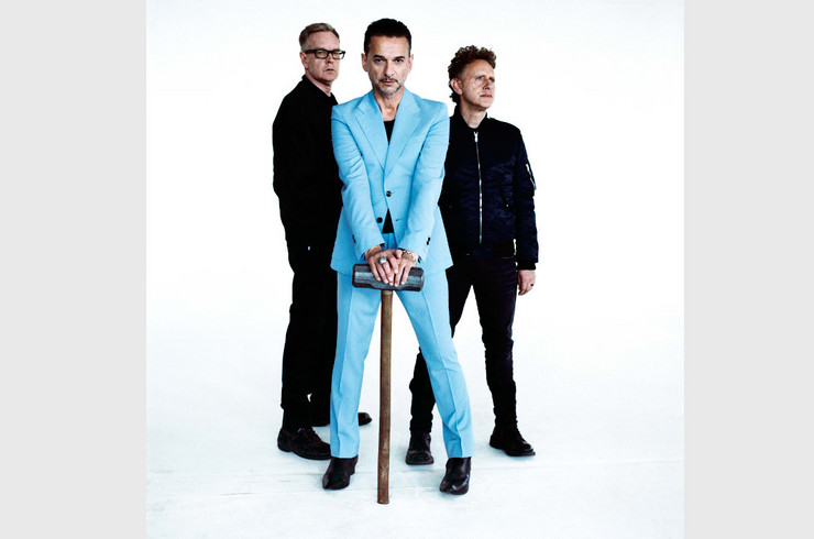 Bandfoto der Gruppe Depeche Mode. Der Sänger sützt sicht auf einen großen Hammer.