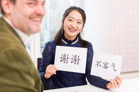 Eine Frau hält Papiere mit chinesischen Schriftzeichen in der Hand, daneben lächelt ein Mann.