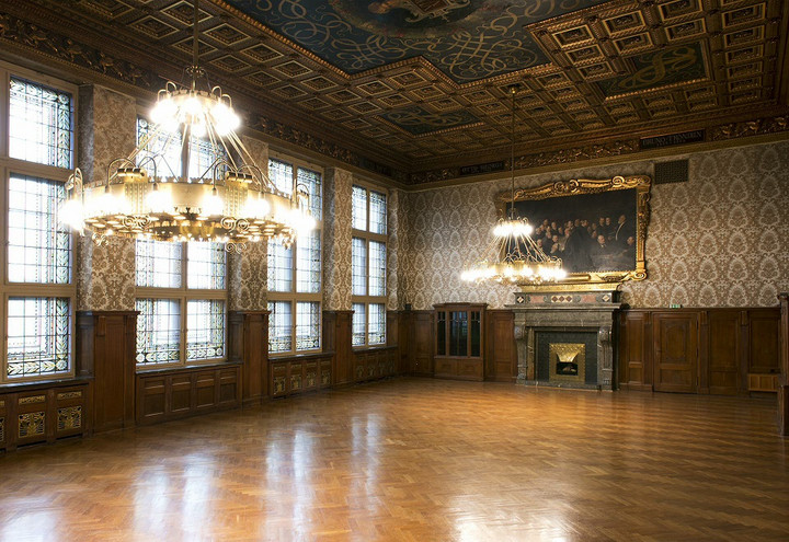 Blick in den leeren prachtvollen Ratsplenarsaal im Neuen Rathaus. Von der aufwendig gestalteten Decke hängen zwei Kronleuchter.
