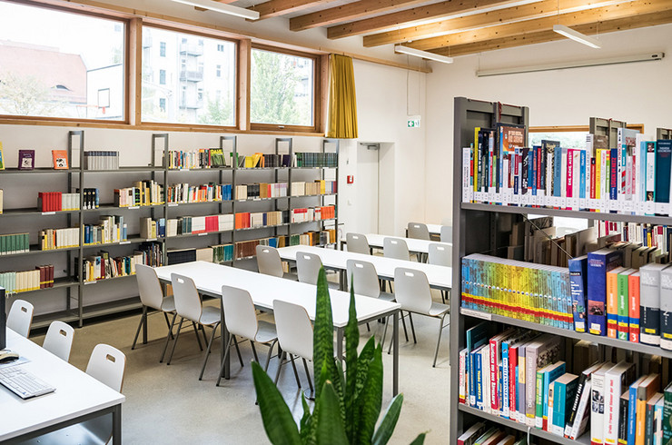 Moderne Schulbibliothek mit Bücherregalen und Computer sowie Tischen