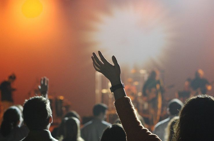 gehobene Hände von Zuschauern, die vor der Bühne während eines Konzertes stehen