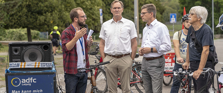 Der Oberbürgermeister unterhält sich mit Fahrradfahrern auf einer Straße