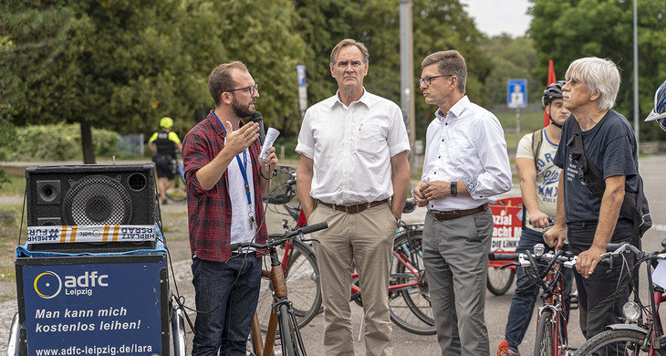 Der Oberbürgermeister unterhält sich mit Fahrradfahrern auf einer Straße