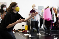 Drei Menschen bei Proben für ein Theaterstück in einem Studioraum mit Kleiderständer