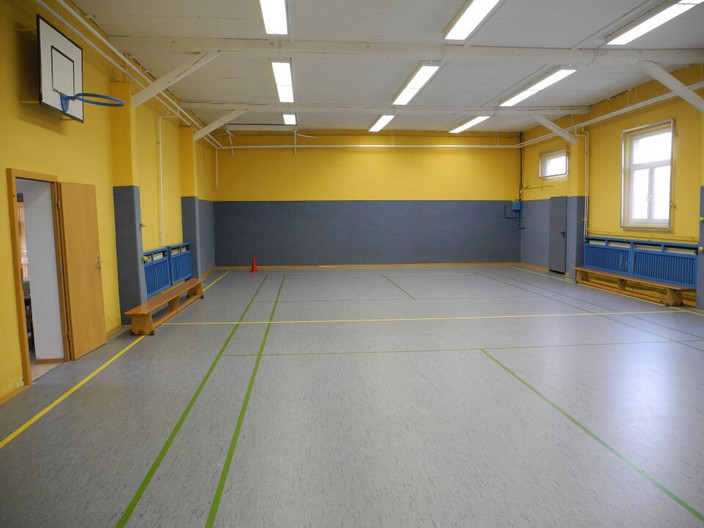 Innenansicht Sporthalle Lützschena mit Spielfläche, Basketballkorb und Bänken