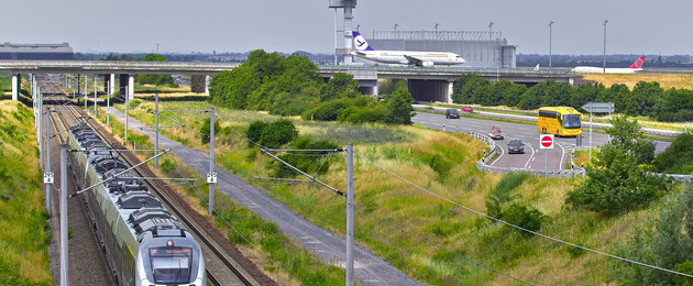 Ein Zug kommt dem Betrachter entgegen, im Hintergrund ist die A14 zu sehen sowie der Flughafen Leipzig Halle