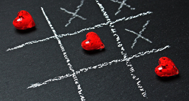 Tic-Trac-Toe Spielfläche mit drei Kreuzen und drei Herzen, die eine Linie bilden.