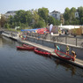 Die Abbildung zeigt den Stadthafen Leipzig bei bestem Wetter. Menschen lassen Boote ins Wasser