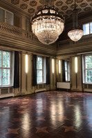 Saal im Parkschloss im Robert-Koch-Park mit dunklen Holzboden und aufwendigen Decken-Kristallleuchtern.