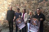 Drei Männer und zwei Frauen mit Plakaten für das Courage-Konzert vor einer Steinmauer