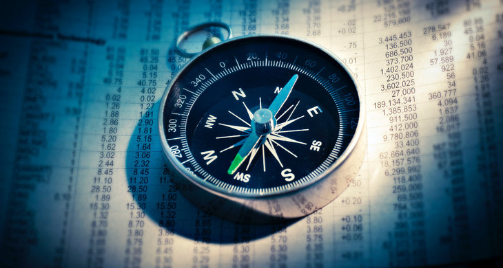 Ein Kompass liegt auf einem Blatt, auf dem tabellarisch Zahlen notiert sind.
