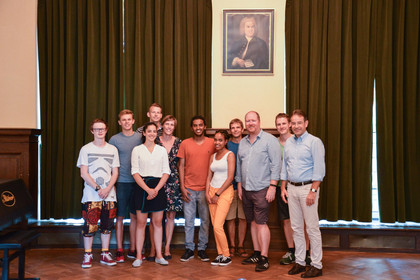 Gruppe von Menschen, die die ersten Stipendiaten aus Addis Abeba in Leipzig in einem Raum der Musikschule begrüßen.