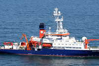 Blaues Schiff mit weißen Aufbauten und roter Takelage auf See.