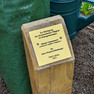 Holzstele mit Plakette, die Informationen zur Baumpflanzung enthält