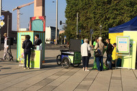 Mehrere Personen stehen an einem Infostand auf einem Platz in der Innenstadt Leipzigs.