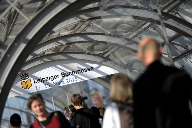 Besucher der Leipziger Buchmesse mit einem Schild Leipziger Buchmesse 2015