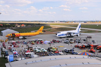 Auf einer betonierten Fläche des Flughafen Leipzig/Halle stehen zwei große Flugzeuge. Davor sind mehrere Fahrzeuge ausgestellt und viele Menschen schauen sich diese an.