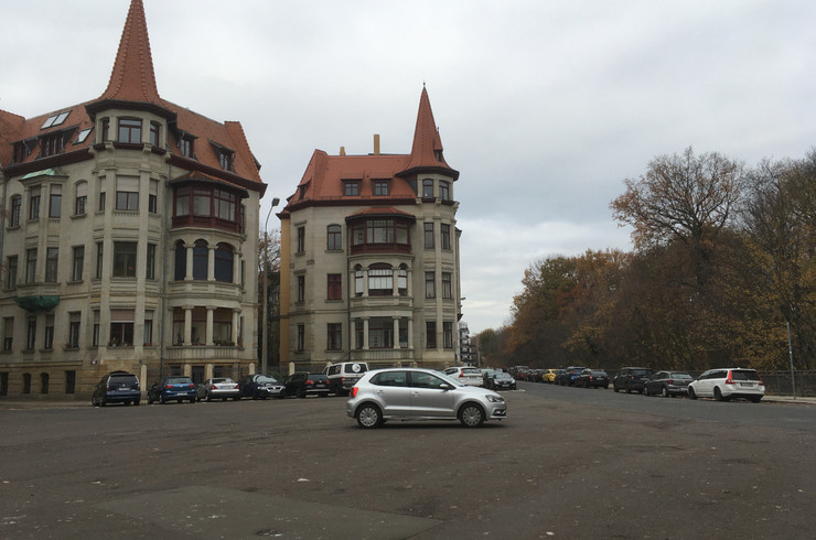 Große Verkehrsfläche des Liviaplatzes mit parkenden Autos. Im Hintergrund befinden sich Wohnhäuser.