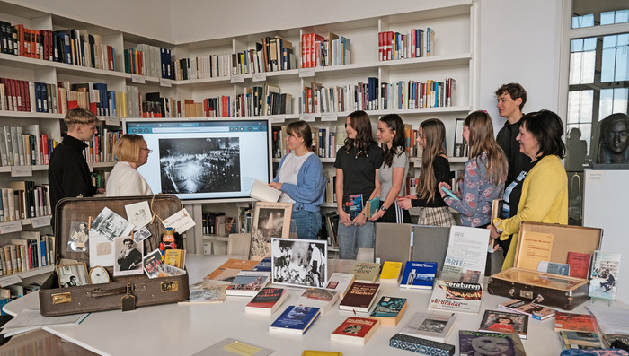 Eine Gruppe Jugendlicher in einer Bibliothek betrachtet ein historisches Foto der Bücherverbrennung auf einem Bildschirm