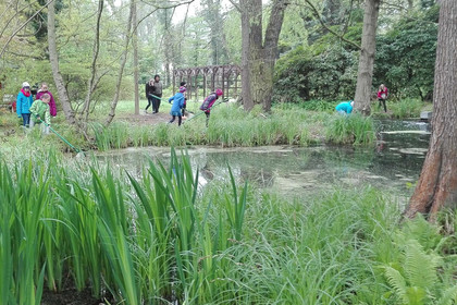 Schüler im Botanischen Lehrgarten. Im Vordergrund ist ein großer Teich.