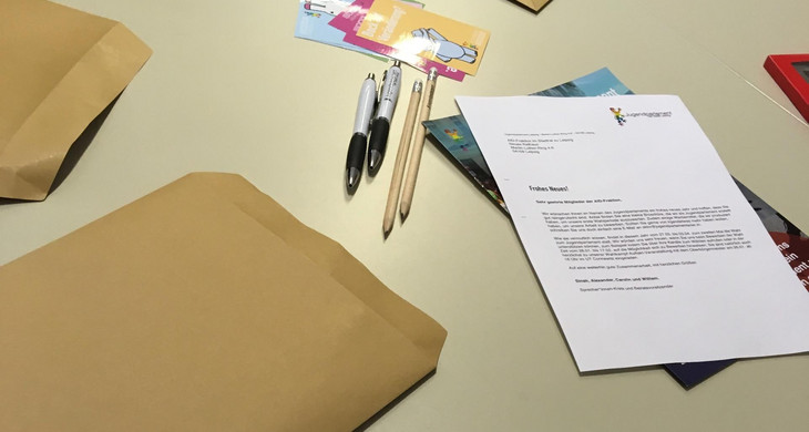 Ein Brief, mehrere Briefumschläge und Stifte liegen auf einem Tisch