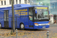 Ein großer blauer Bus mit der Aufschrift Fahrbibliothek steht auf einem Platz neben einer Straße.