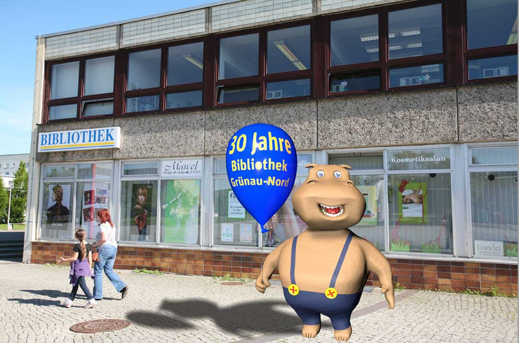 Bibliotheksmaskottchen (ein Nilpferd mit Latzhose) steht mit Luftballons in der Hand vor der Bibliothek Grünau Nord.