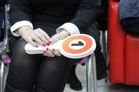 Eine Frau sitzt auf einem Stuhl und hält Bieterkarten für eine Auktion in der Hand.