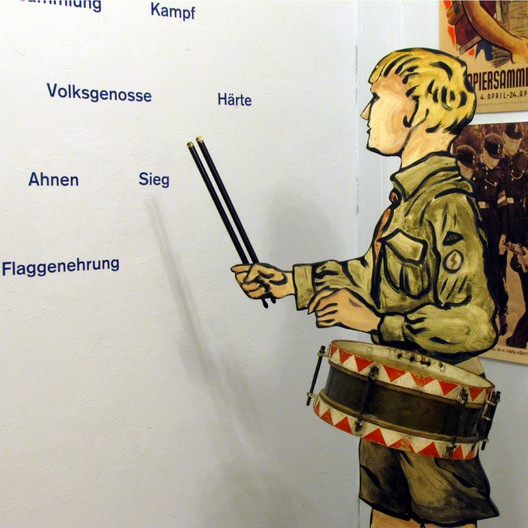 Detail des ausstellungsraums "Schule unterm Hakenkreuz". Mit Figurine in HJ-Uniform, mit Trommel und Schlägeln vor einer Propagandawand.