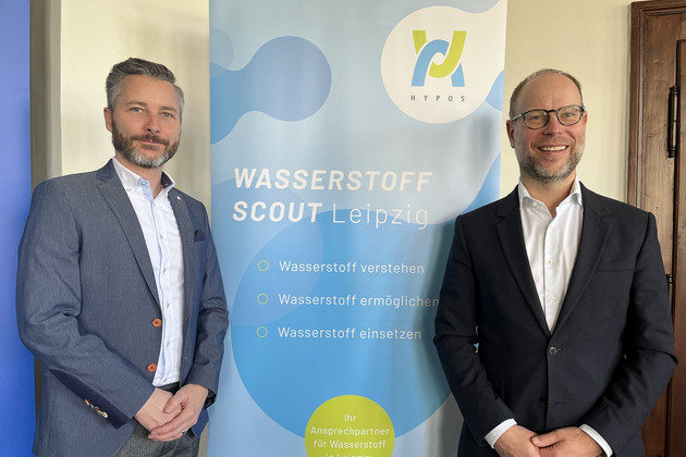 Vor einem Aufsteller des HYPOS e.V. stehen Leipzigs Wasserstoff Scout Andreas Bauer und Wirtschaftsbürgermeister Clemens Schülke