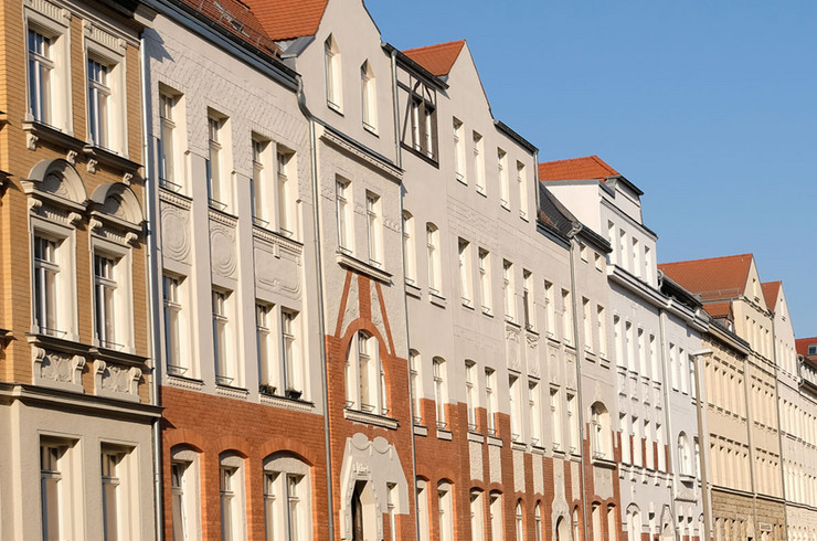 Eine Ansicht von Fassaden von sanierten Gründerzeithäusern ist von Sonnenlicht beleuchtet.