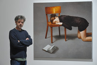 Hans Aichinger neben einem Bild einer schwarz gekleideten Frau, die ihren Kopf auf einen Holzstuhl legt