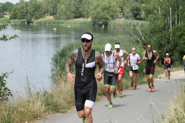 Mehrere Sportler laufen am Kulkwitzer See entlang.
