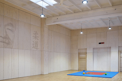 Innenraumgestaltung der Judohalle mit Wandgestaltung. Durch Perforation entstehen Schriftzeichen und das Konterfei des Judo-Begründers.